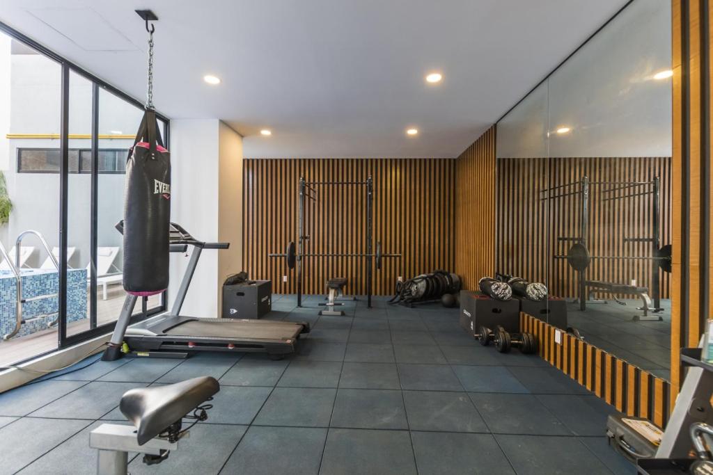 einen Fitnessraum mit Kardiogeräten und einem Pool in der Unterkunft Central Balbuena Apartments in Guadalajara