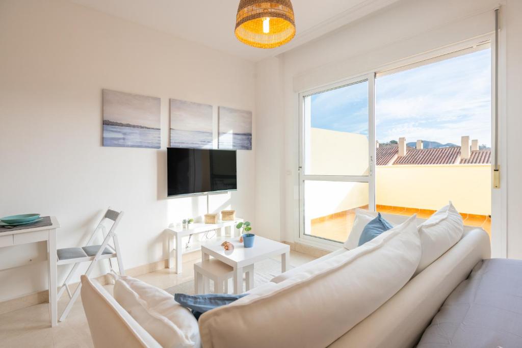 a living room with a white couch and a large window at Renthas Añoreta Golf Beach in Torre de Benagalbón