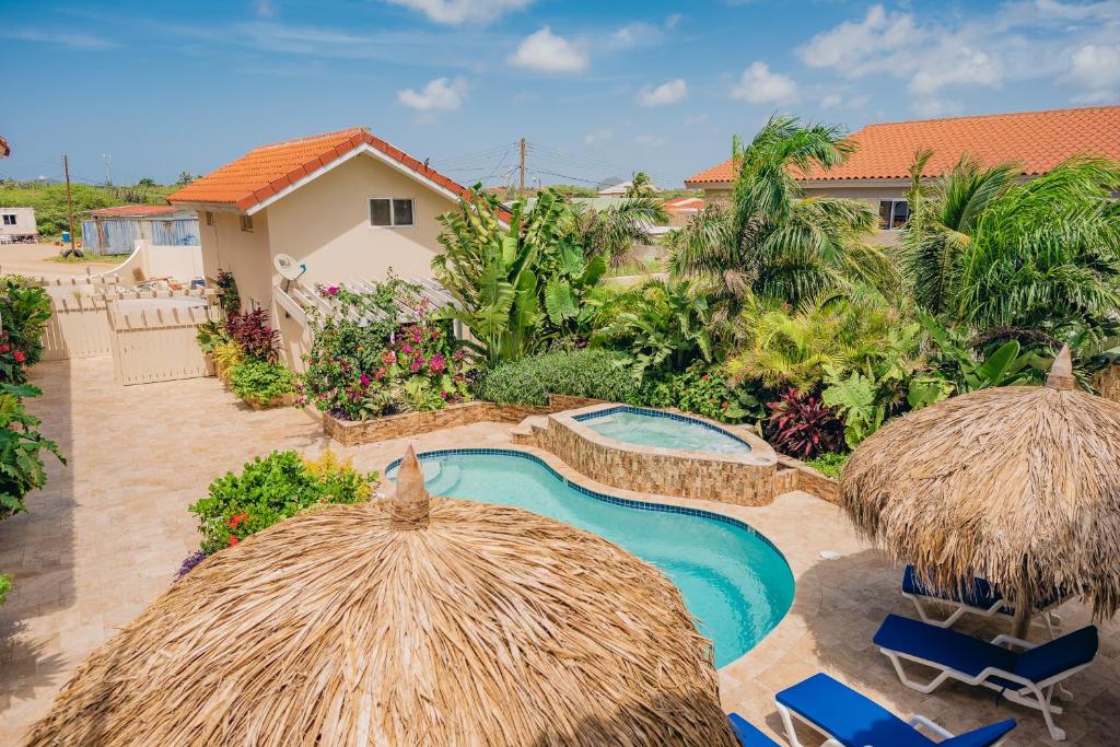 um resort com uma piscina e dois guarda-sóis de palha em Spacious 4-bedroom apartment 2 km from Eagle beach em Palm-Eagle Beach
