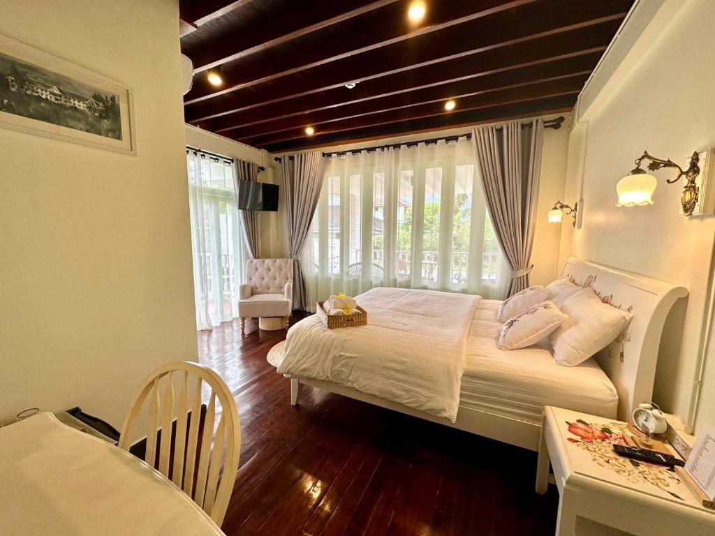 a bedroom with a bed and a table and a chair at Zane Balcony House Ranong Hotel เซน บัลโคนี่ เฮ้าส์ ระนอง in Ban Lum Than