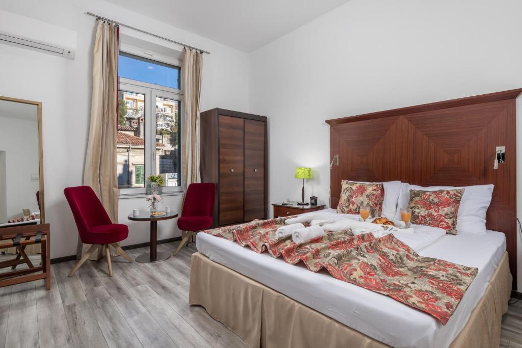 1 dormitorio con 1 cama grande y 2 sillas rojas en Continentale - Deluxe Rooms en Rijeka