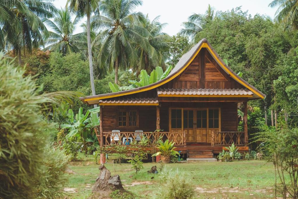 a small wooden house in a field with palm trees at Kohjum Freedom Resort in Ko Jum