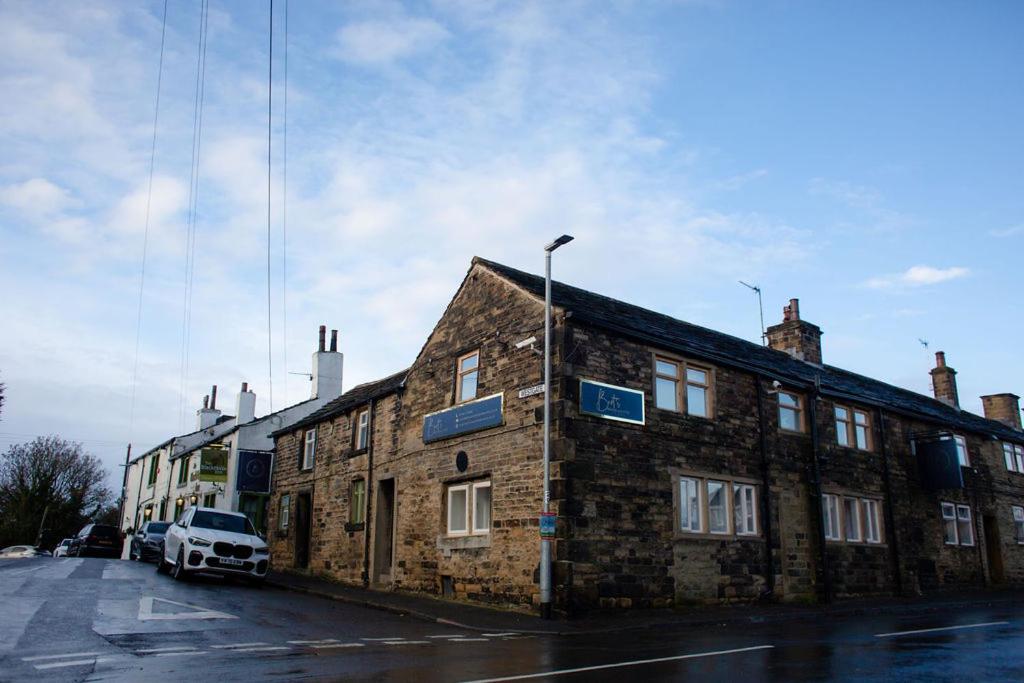 a brick building with a white car parked next to it at Bert's Rooms at The Black Horse Inn in Brighouse