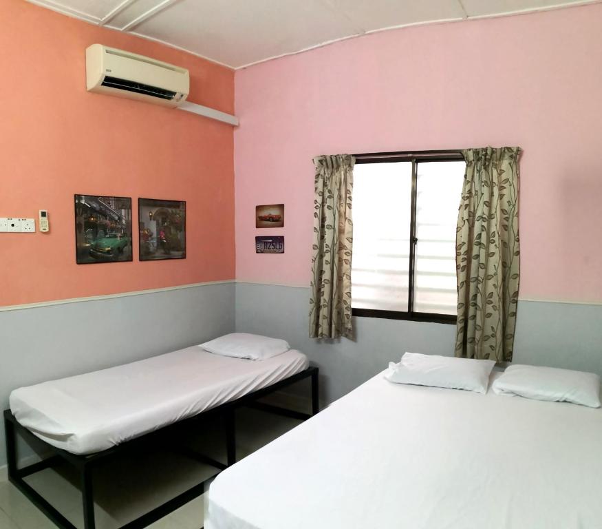 two beds in a room with a window at Hua Tang Homestay in Ipoh