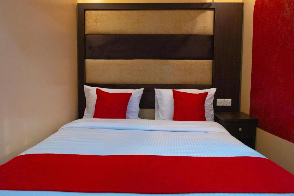 a bedroom with a red and white bed with red pillows at Gardens Executive Suites in Kikuyu