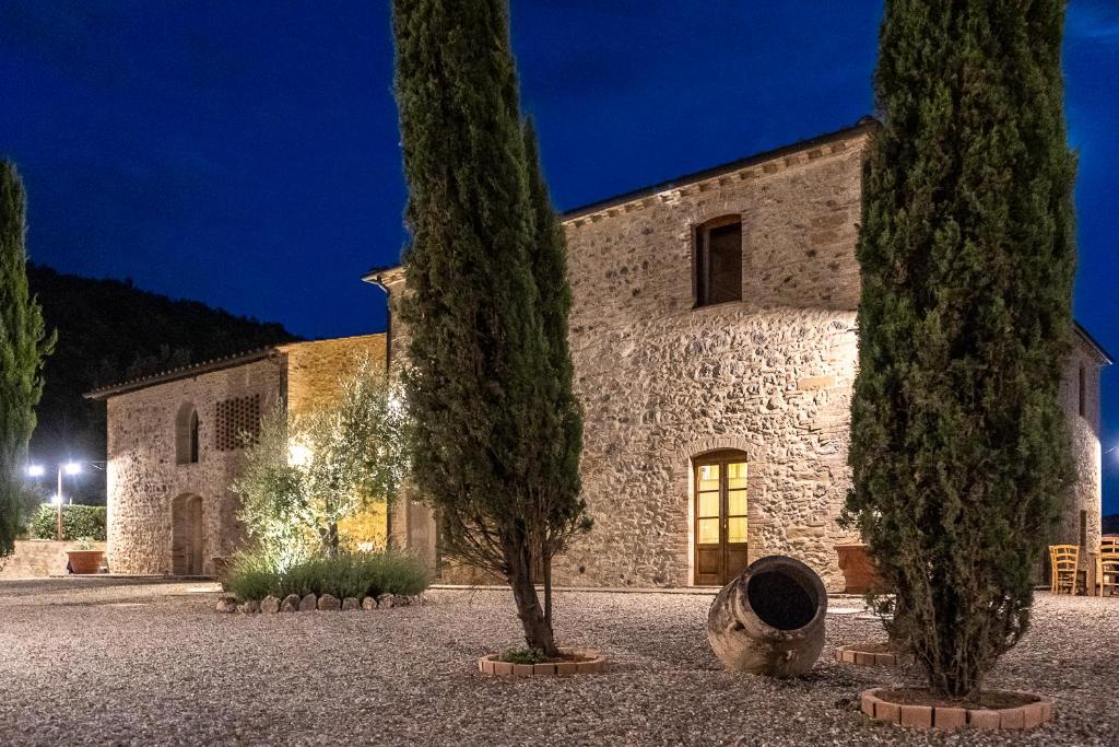 un vieux bâtiment en pierre avec deux arbres devant lui dans l'établissement Exclusive Villa with pool Borgo Pian di Sala, à San Gimignano