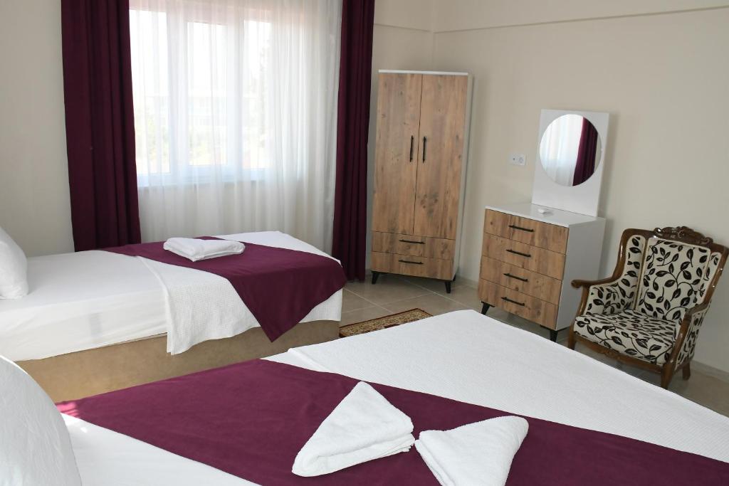 a bedroom with two beds and a chair and a mirror at The Titanic hause otel in Pamukkale