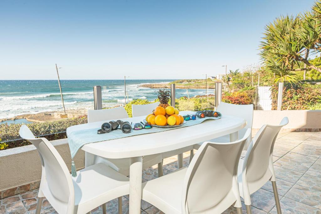 a white table and chairs with the beach in the background at LA CRETE SANDS NO 7 in Uvongo Beach