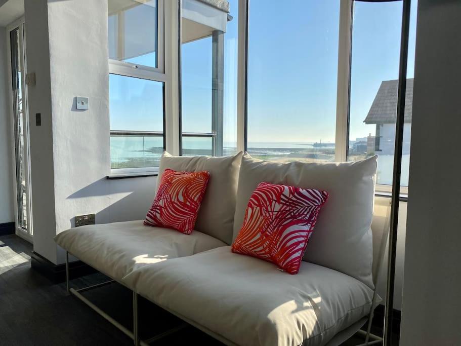 a white couch with two red and white pillows on it at The Sun Deck Apartment - Westbrook Bay Beach - By Goldex Coastal Breaks in Kent