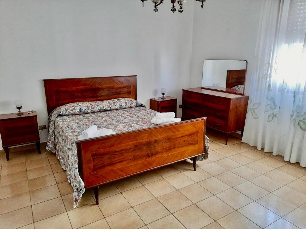 um quarto com uma cama, 2 cómodas e um espelho em Nonna Teresa em Surbo