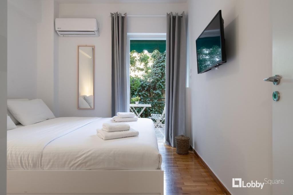 biała sypialnia z łóżkiem i oknem w obiekcie Aether Apartment by LobbySquare w Atenach