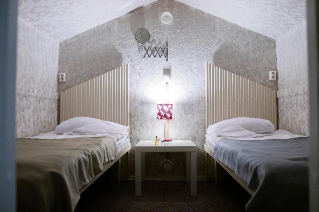 a room with two beds and a table with a lamp at Hotel Teltta in Orimattila