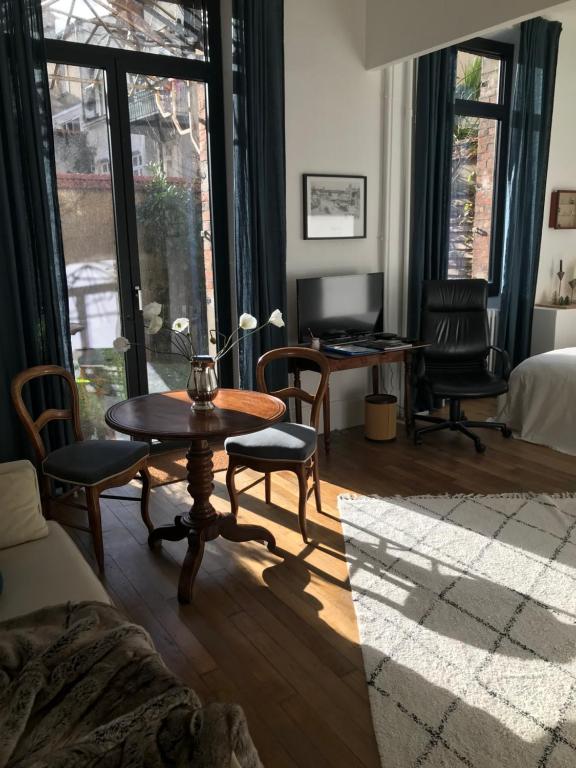 ein Wohnzimmer mit einem Tisch, Stühlen und einem Bett in der Unterkunft LE JARDIN D'ALEXANDRE in Orléans
