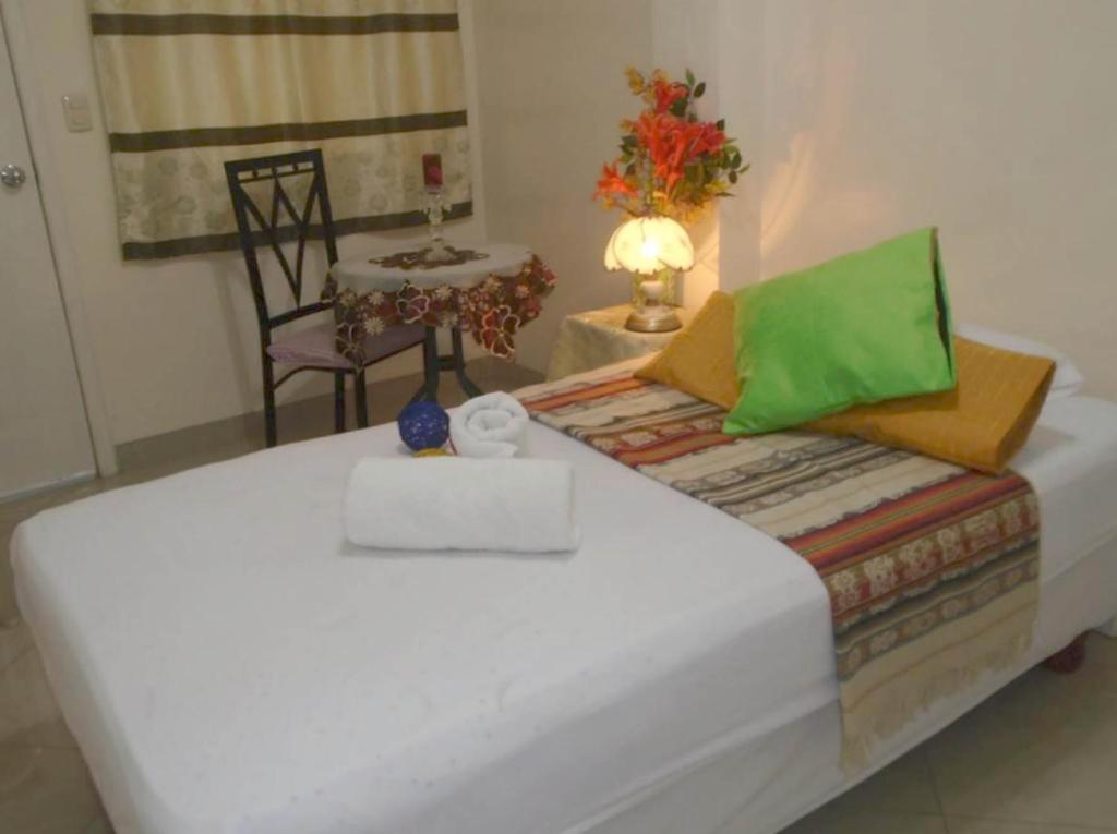 a bed in a room with a table and a chair at Jeshua Simmonds Inn in Guayaquil