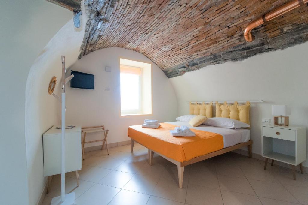 ein Schlafzimmer mit einem Bett mit einer orangefarbenen Decke in der Unterkunft La casa dei tre pesci - Appartamento Alborella in Torno