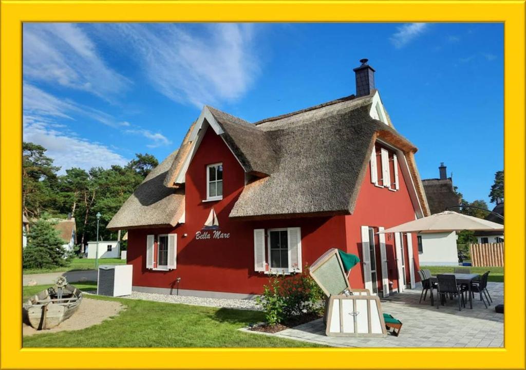 una casa rossa con tetto grigio e patio di Modernes Reetdach-Ostseeferienhaus Bella Mare, Insel Usedom mit Sauna, Kamin & Sonnenterrasse a Zirchow