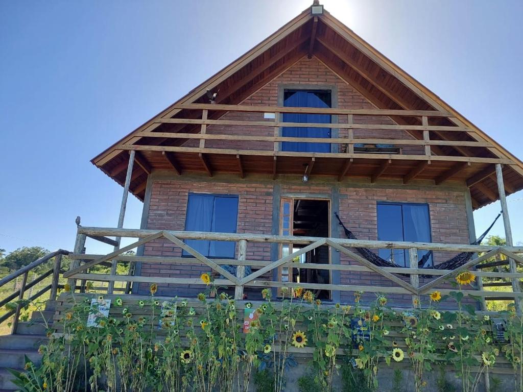 una casa con techo de paja en un campo de girasoles en Chácara Bela Vista en Taquara