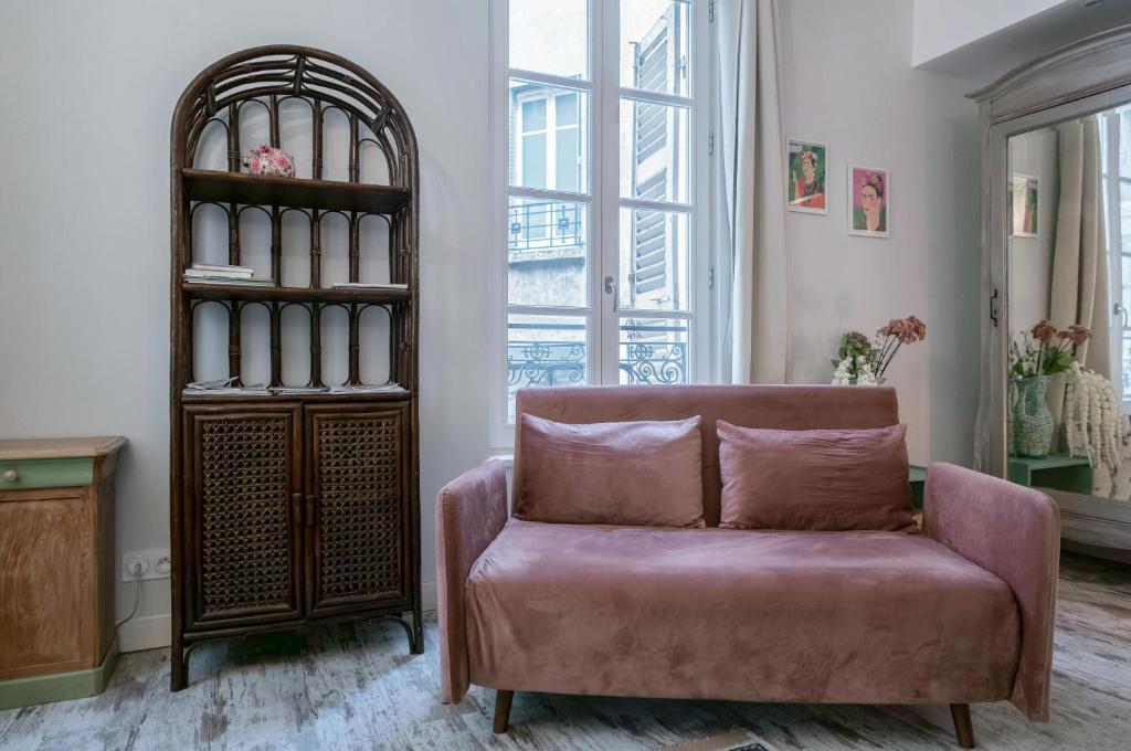 - un salon avec un canapé rose et une étagère à livres dans l'établissement Résidence Aristide Briand - Appartements en Centre Ville, à Vichy