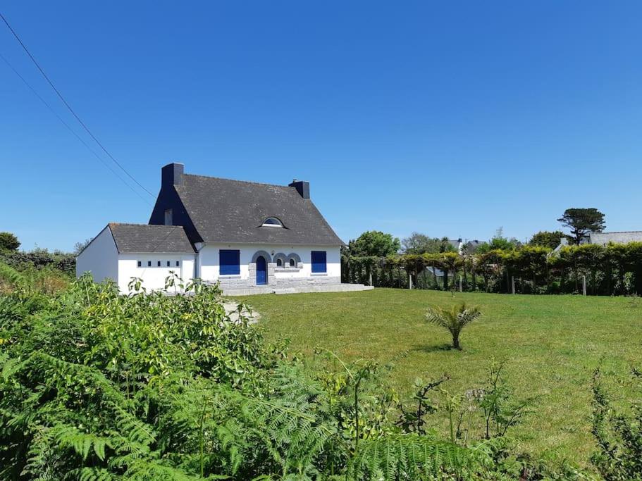 uma casa branca com um telhado preto num campo em Maison bord de mer em Plouguerneau