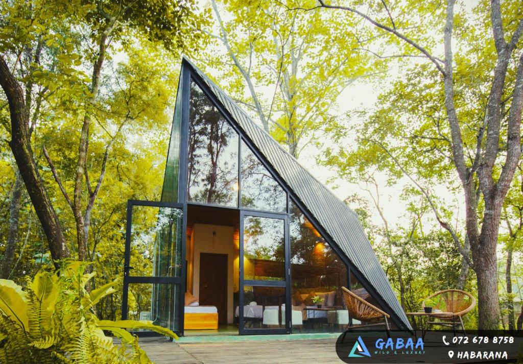 a glass house with a geometric roof in a forest at Gabaa Resort & Spa - Habarana in Habarana