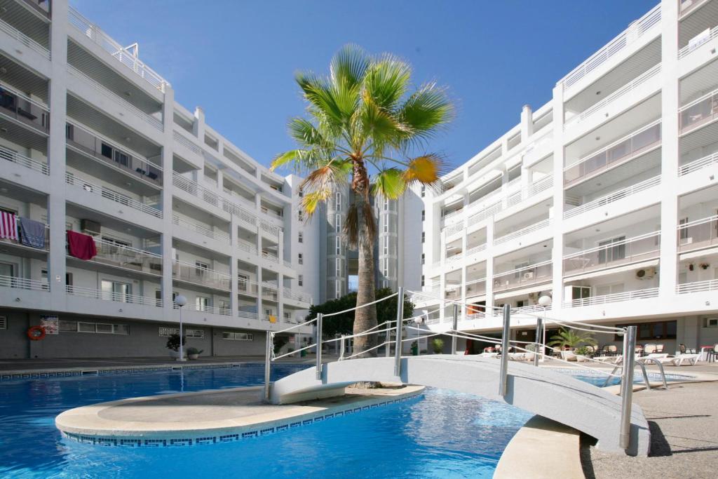 a large apartment building with a swimming pool and a palm tree at Rentalmar Royal in Salou