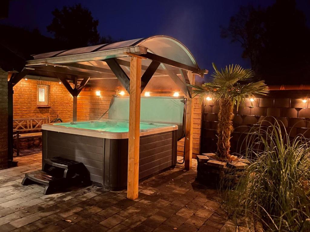 a hot tub with an umbrella in a backyard at night at Vakantiehuis de Heide in Bergen op Zoom