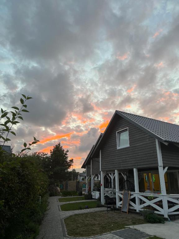 a house with a sunset in the sky behind it at Lawendowe domki in Karwia