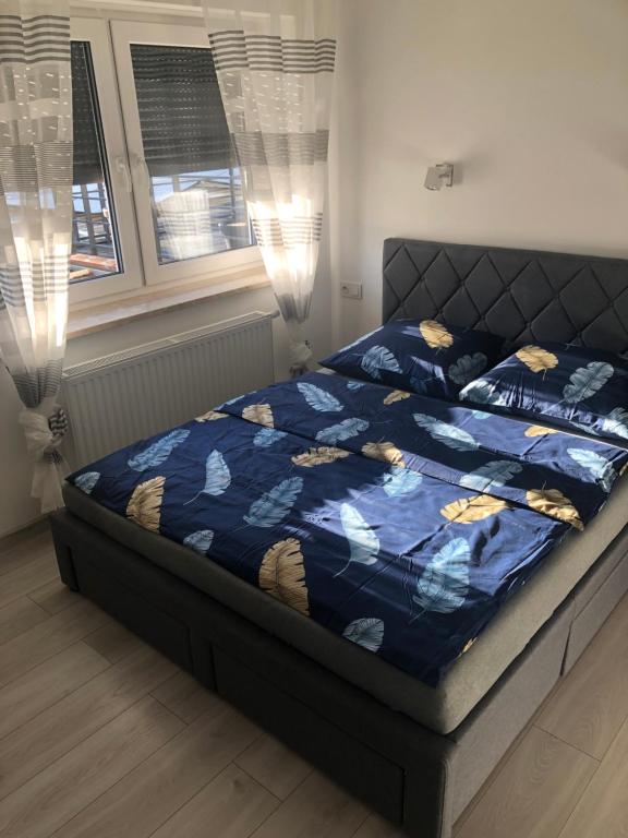 a bed with a blue comforter and two windows at Willa Euforia in Poznań