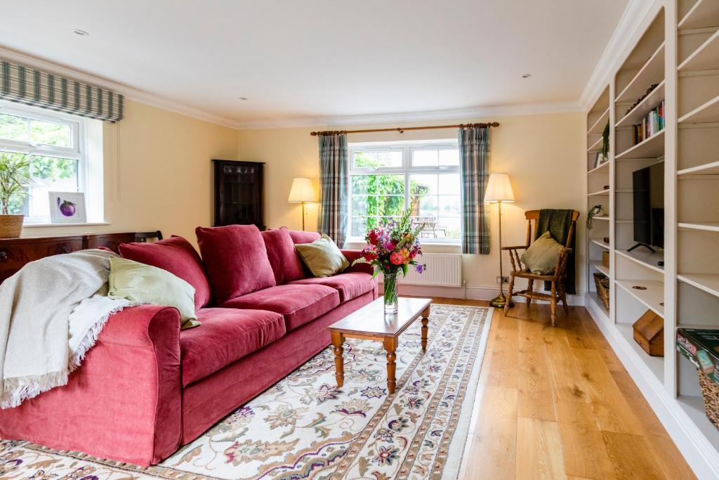 a living room with a red couch and a table at The Honeypot at Newlands in Bury in Bury