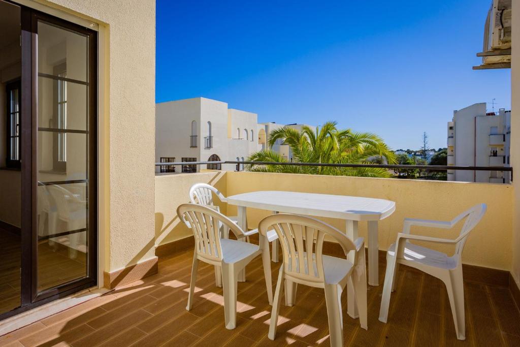 d'une table et de chaises blanches sur un balcon. dans l'établissement Quinta dos Arcos 2BR w/ AC & Pool by LovelyStay, à Alvor