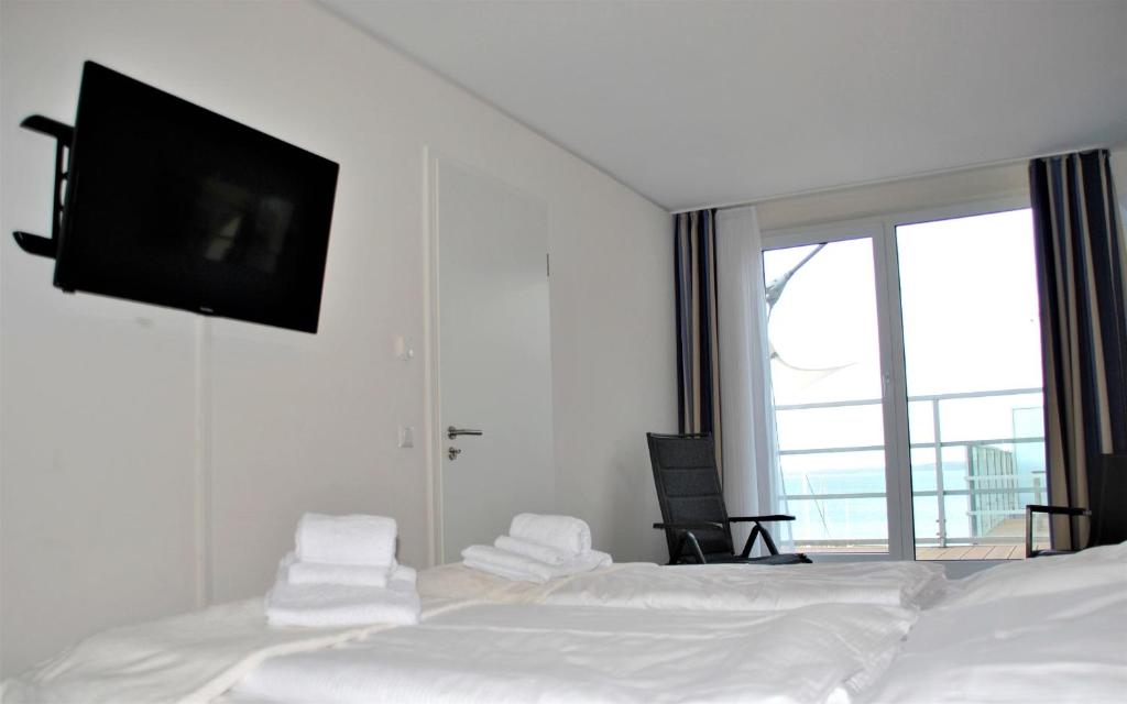 um quarto com uma cama e uma televisão de ecrã plano na parede em Apartmenthaus Hafenspitze Ap 42 "Segler", mit Sauna, Blickrichtung offene See - a72332 em Eckernförde