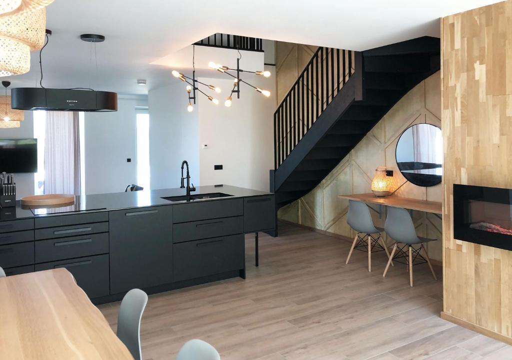 a kitchen with black cabinets and a staircase at Bramendijk in Groede