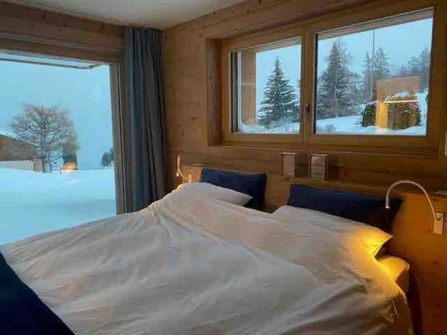 a bedroom with a white bed and a window at Ski in out Swiss Alps Chalet Charelle by Jolidi in Nendaz