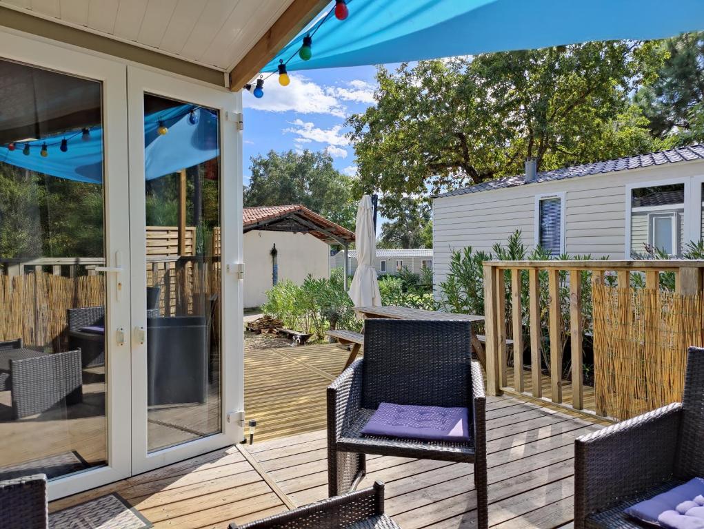 a deck with chairs and an umbrella at Mobile-Home 6 personnes Cap Ferret in Claouey