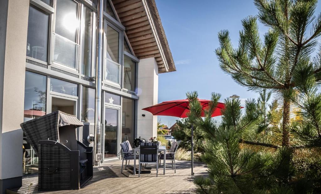a patio with a table and a red umbrella at Traumhaus Heiligenhafen in Heiligenhafen