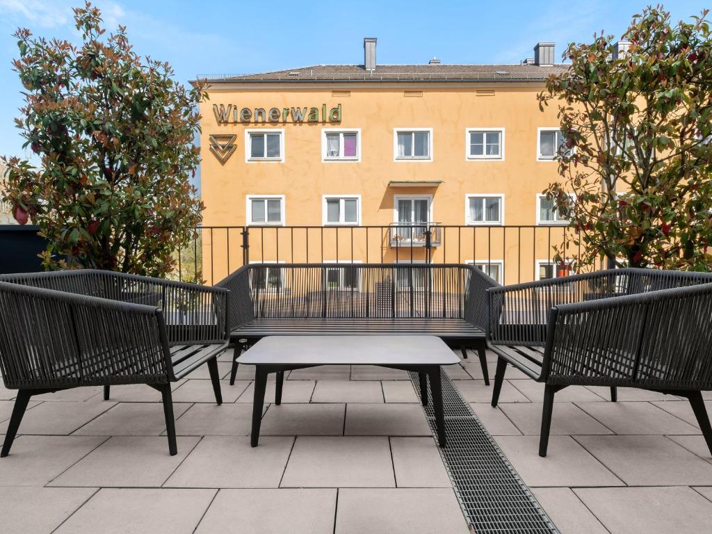eine Gruppe von Bänken, die auf einer Terrasse mit einem Gebäude sitzen in der Unterkunft numa I Stark Rooms & Apartments in München