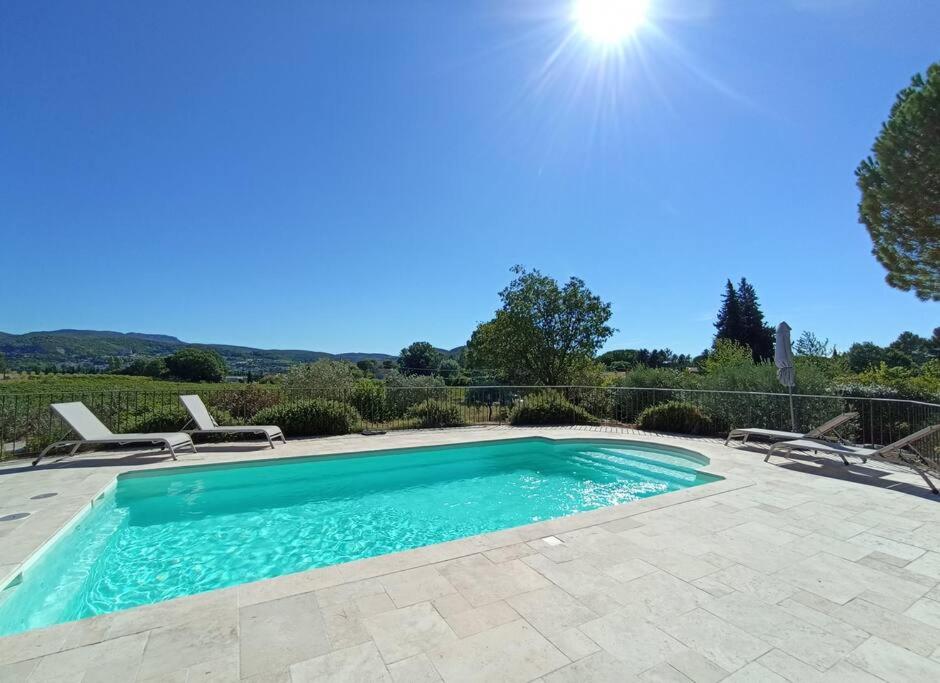 a swimming pool in a yard with chairs around it at Gite Himaya - Vaison la Romaine in Vaison-la-Romaine