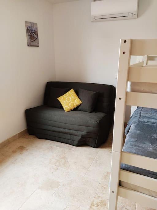 a black couch with a yellow pillow in a room at Gite Himaya - Vaison la Romaine in Vaison-la-Romaine