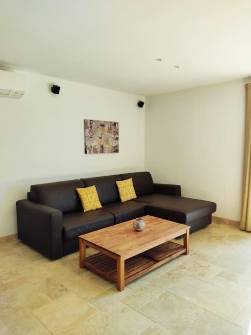 a living room with a black couch and a coffee table at Gite Himaya - Vaison la Romaine in Vaison-la-Romaine