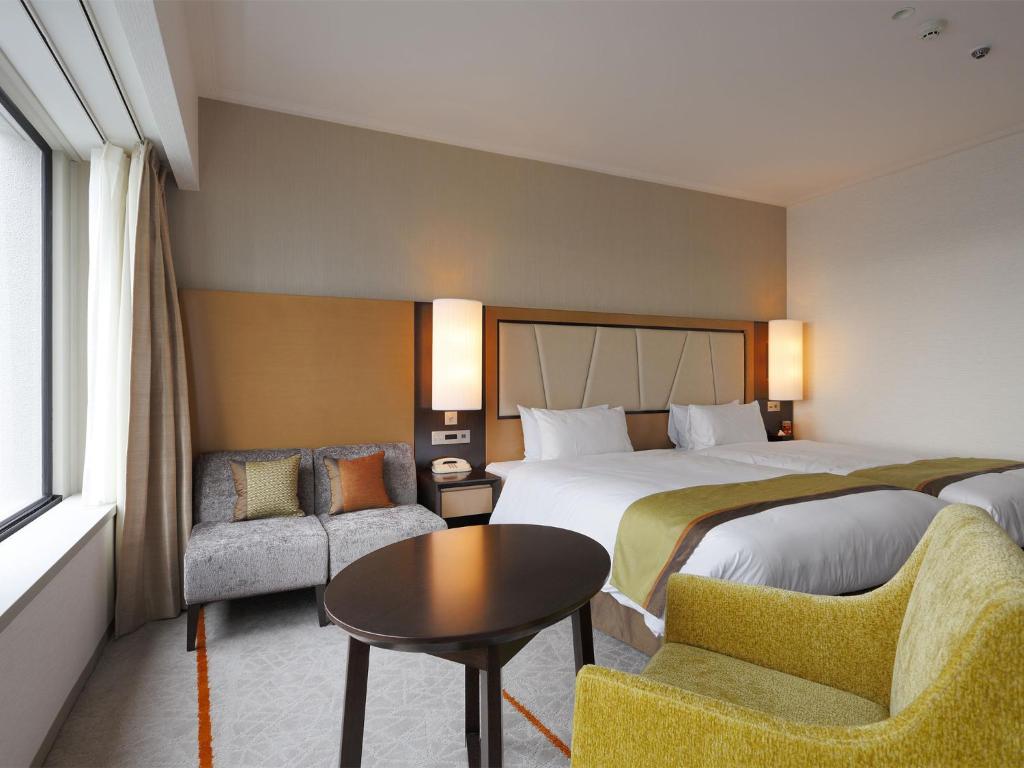 a hotel room with two beds and a table and chairs at Keio Plaza Hotel Tokyo in Tokyo