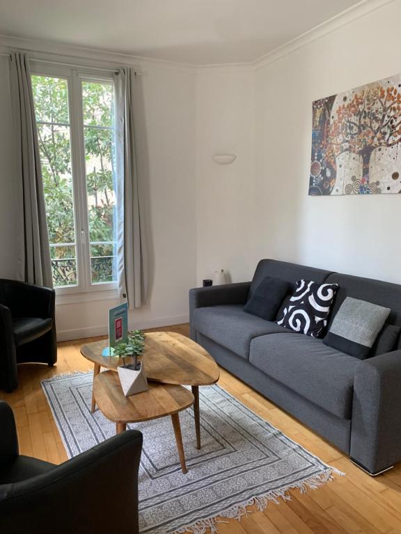 un salon avec un canapé bleu et une table dans l'établissement Nice Grand appartement face jardin, à Nice