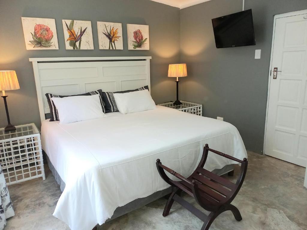 a bedroom with a large white bed and a chair at Bush Willow Suite - Villa Roc Guesthouse, Salt Rock Ballito Solar Power in Salt Rock