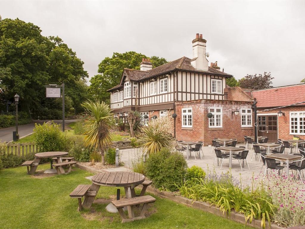 a building with picnic tables and chairs in a garden at The Fishbourne in Fishbourne