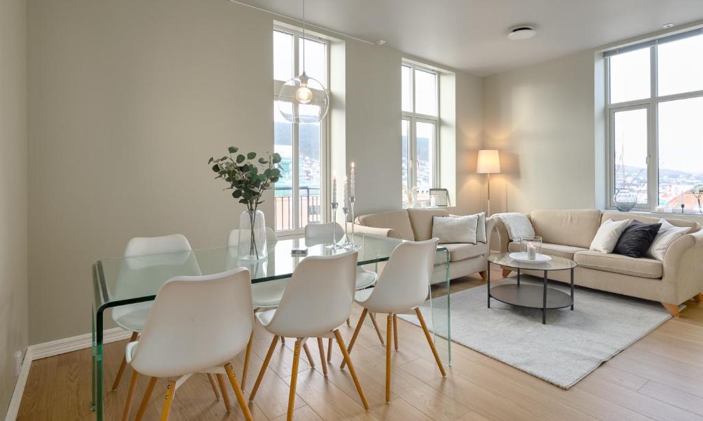 ein Wohnzimmer mit einem Glastisch und weißen Stühlen in der Unterkunft Elegant Bergen City Center Apartment - Ideal for business or leisure travelers in Bergen