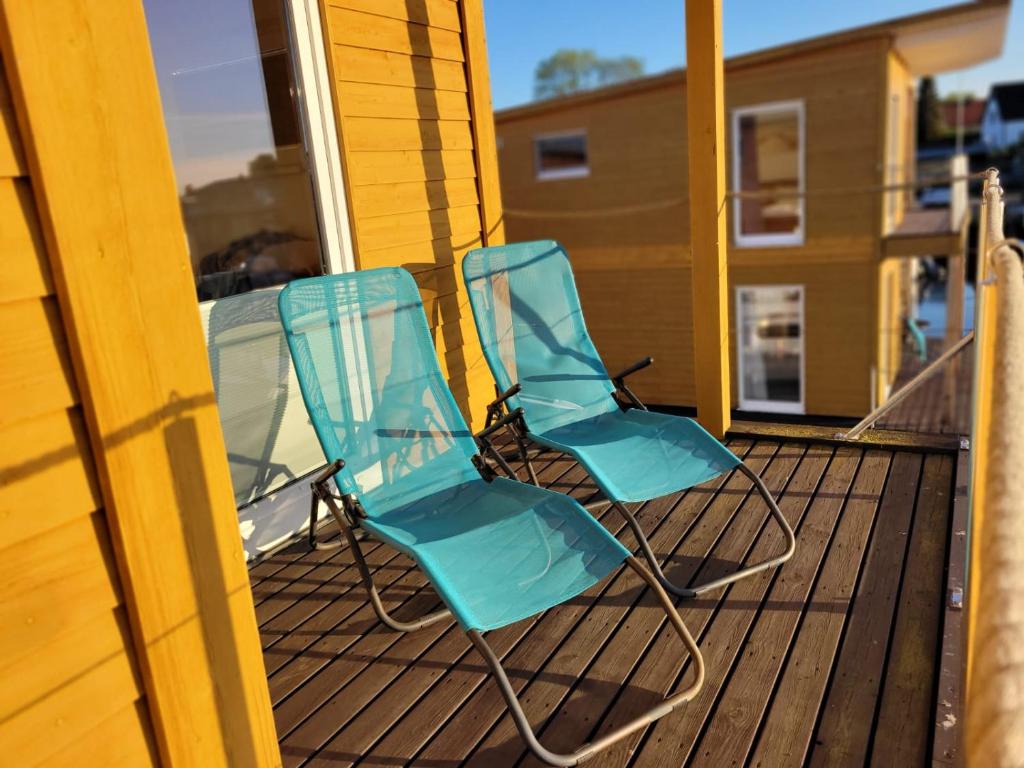 - deux chaises bleues assises sur une terrasse couverte dans l'établissement 4 Sterne Dtv Floating House, à Kröslin