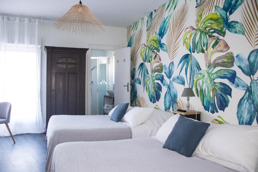 a bedroom with two beds and a mural of plants at Hôtel Restaurant L'Atelier des Cousins in Châtelaillon-Plage
