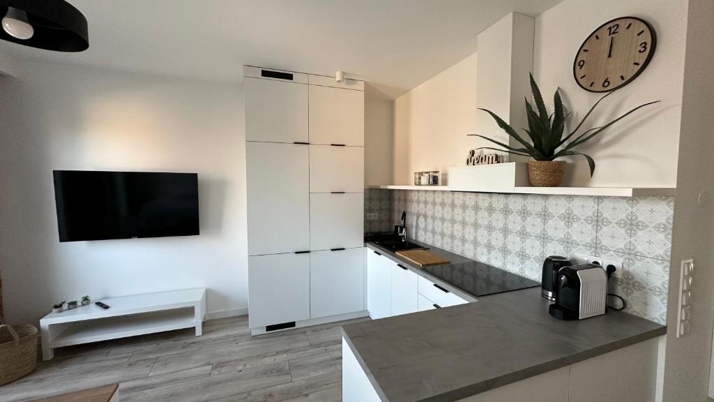 a kitchen with white cabinets and a clock on the wall at Apartamenty Mickiewicza40 in Śrem