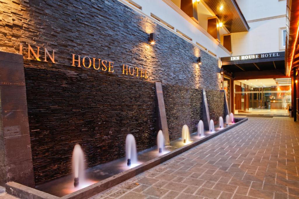 eine Backsteinmauer mit einem Schild, das Gasthaus Hotel liest in der Unterkunft Inn House- SHA Extra Plus in Pattaya