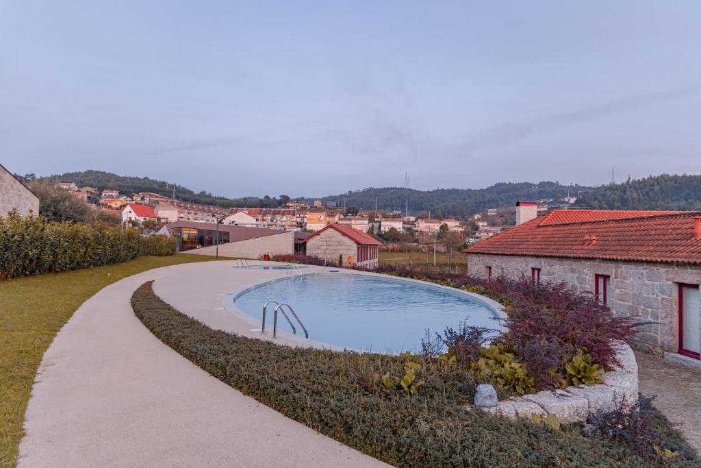 a swimming pool in a garden next to a building at Quinta da Corredoura, Hotel Rural in Guimarães