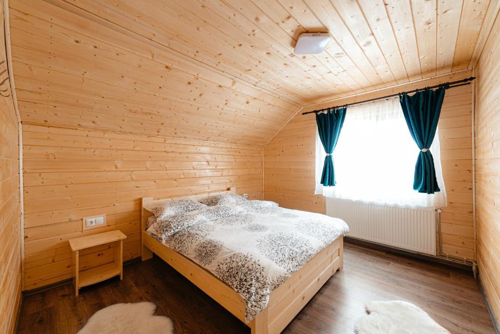 1 dormitorio con 1 cama en una habitación de madera en Flori din Deal, en Mărgău